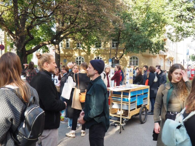 Blick auf viele Personen, die in der Straße stehen und miteinander reden.