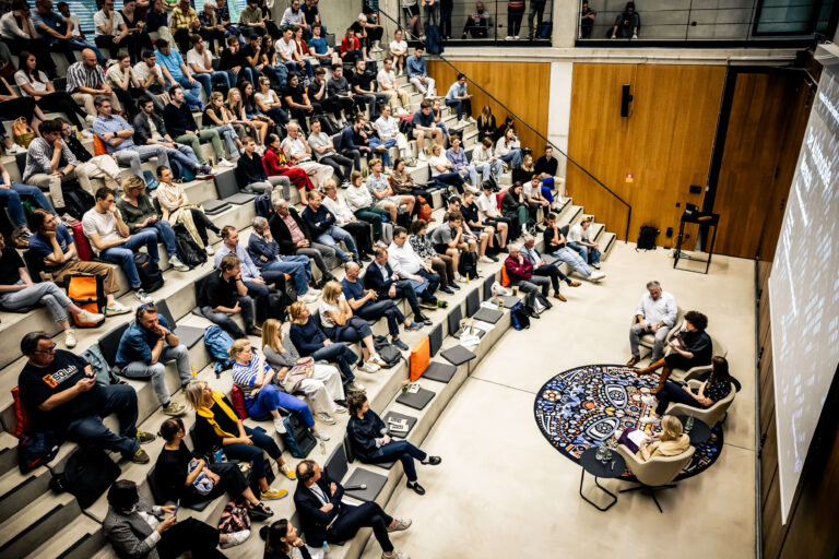 Das Foto zeigt eine Podiumsdiskussion und den Innenraum einer Aula bei der MCube Speaker Series, bei der der Film „Der automobile Mensch“ gezeigt wurde