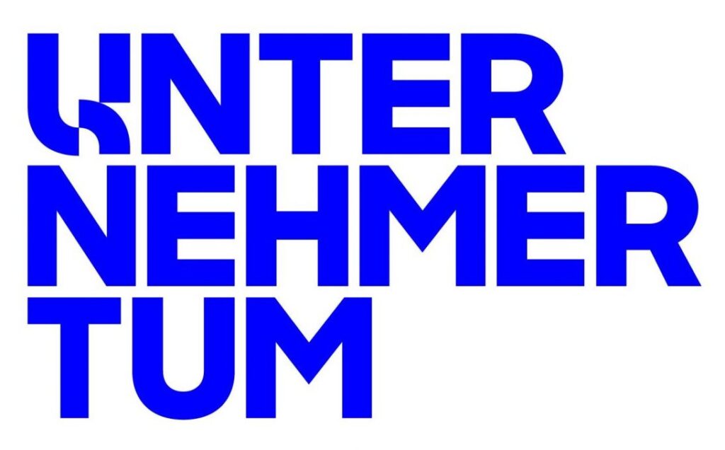 Das Logo besteht aus dem Wort "UNTERNEHMERTUM" in Großbuchstaben, die fett und in kräftigem Blau dargestellt sind. Die Buchstaben sind in drei Zeilen aufgeteilt: "UNTER" in der ersten, "NEHMER" in der zweiten und "TUM" in der dritten Zeile. Das "U" in "UNTER" ist grafisch gestaltet, wobei der linke Teil des Buchstabens wie eine fließende Linie aussieht, die in den Buchstaben integriert ist.